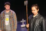 A man stands next to a woman holding an ax in a cemetery in a scene from (Sc)are We Delicious