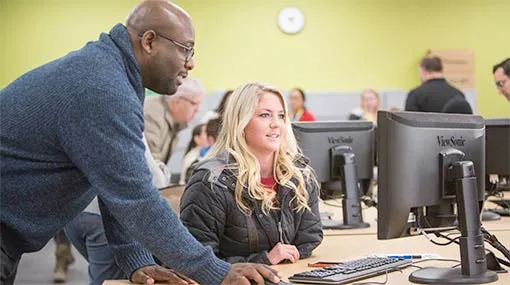 Student getting help on a computer from staff
