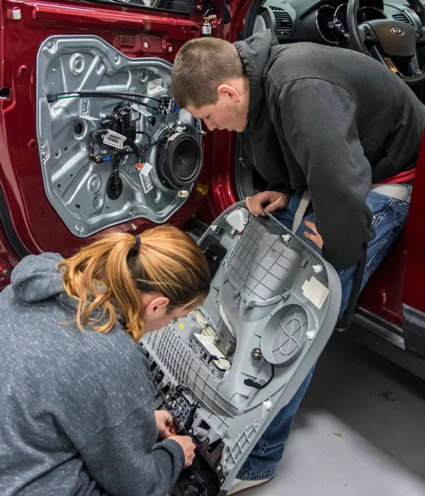 auto collision repair students replacing a car's interior door casing