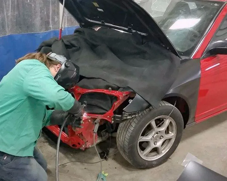 student perfecting their auto body welding skills on a car's front end