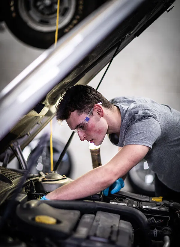 automotive technology student running a diagnostic test on a car engine