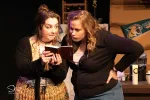 Two women looking at a small book in a scene from Bad in Bed