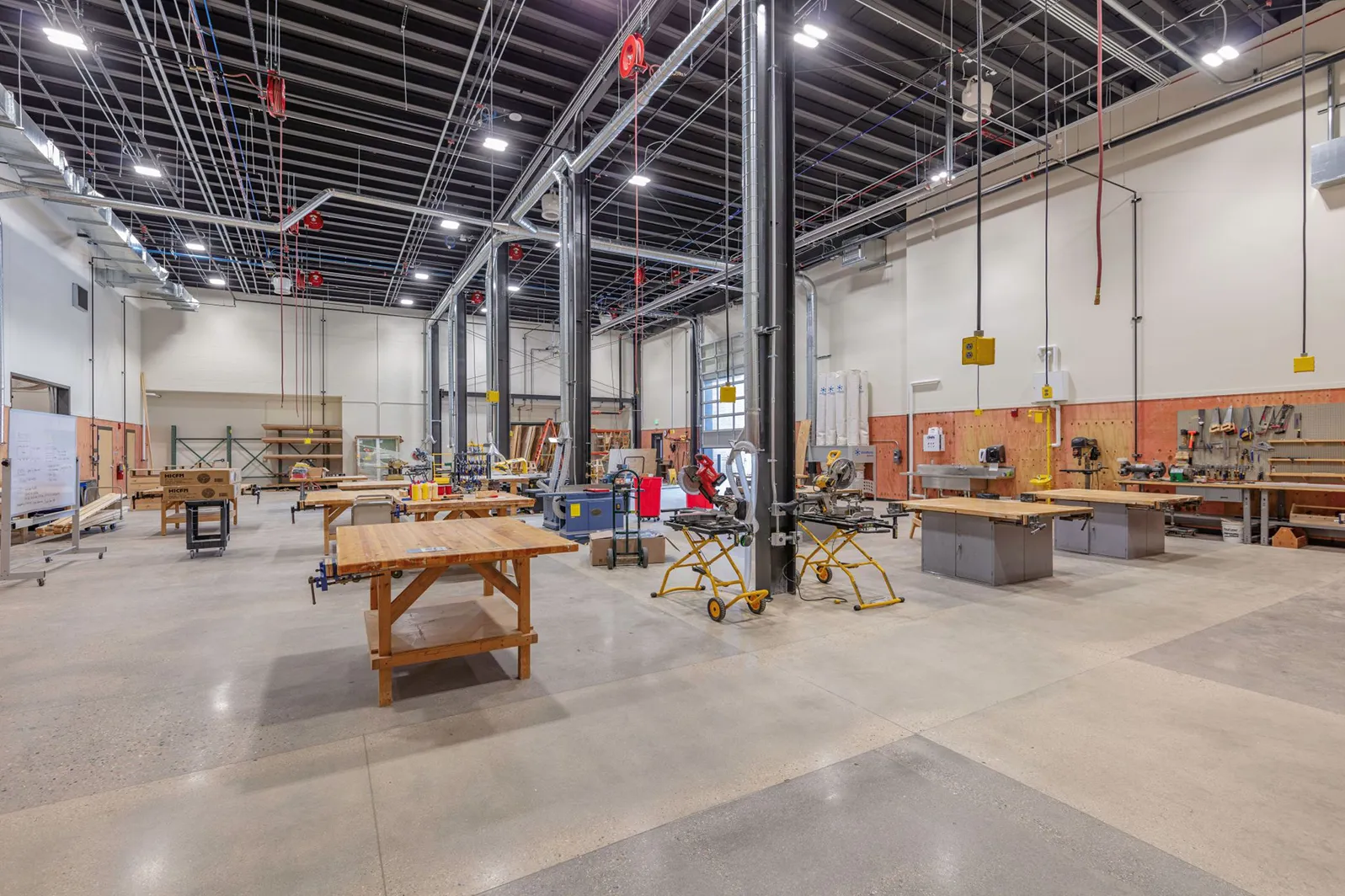 Interior image of new construction and remodeling facility with work benches, machinery and high ceilings.