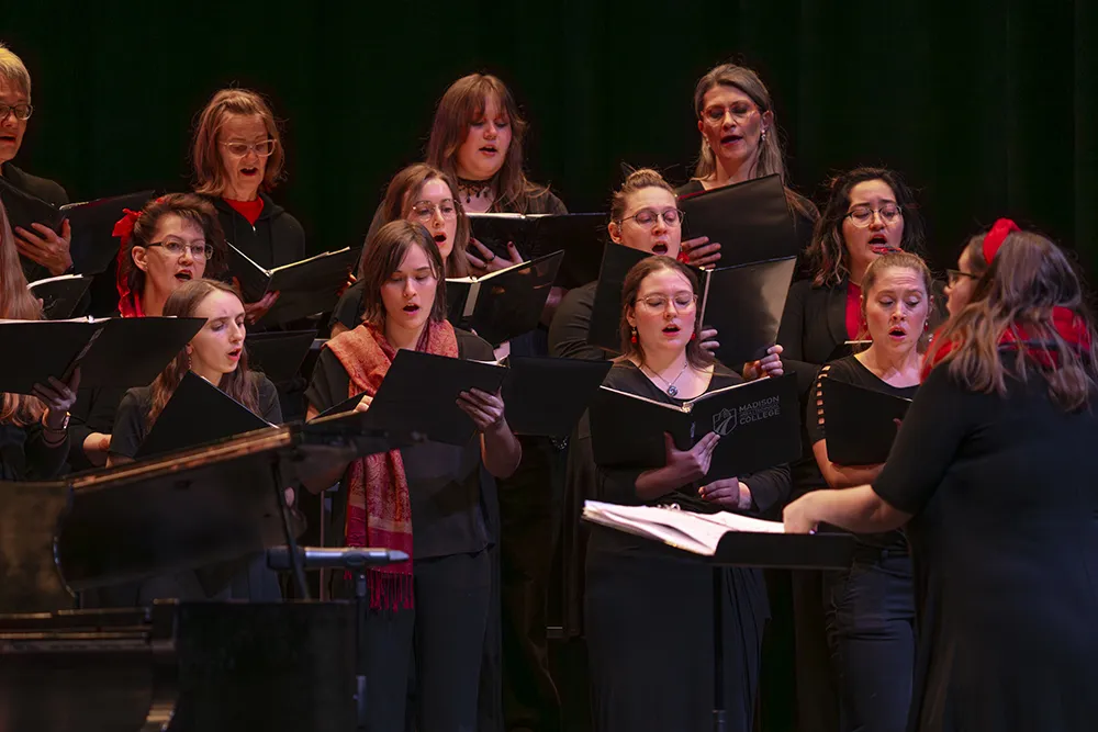 Members of the Madison College Choral Collective holding music books as they are singing