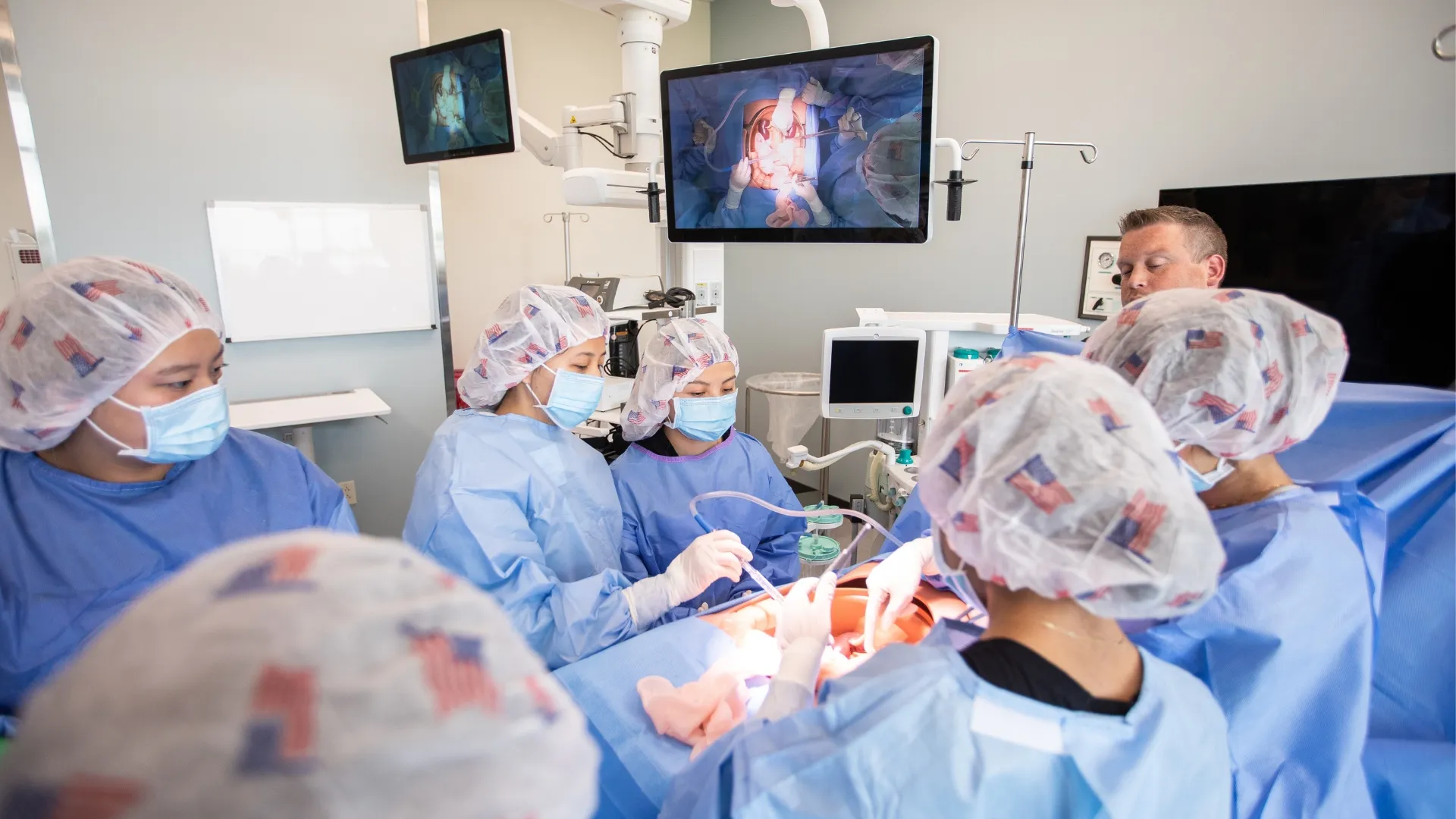 Students in surgical tech lab holding medical instruments and wearing blue scrubs.
