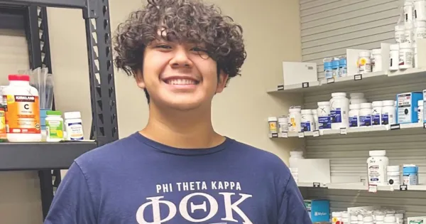 Student intern smiling, posing for camera in a pharmacy clinic.