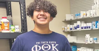Student intern smiling, posing for camera in a pharmacy clinic.
