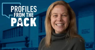 Christa Duren smiling with a blue background of the HPS building in the background and the Profiles from the Pack logo to the left side.