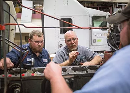 three people looking at an engine part