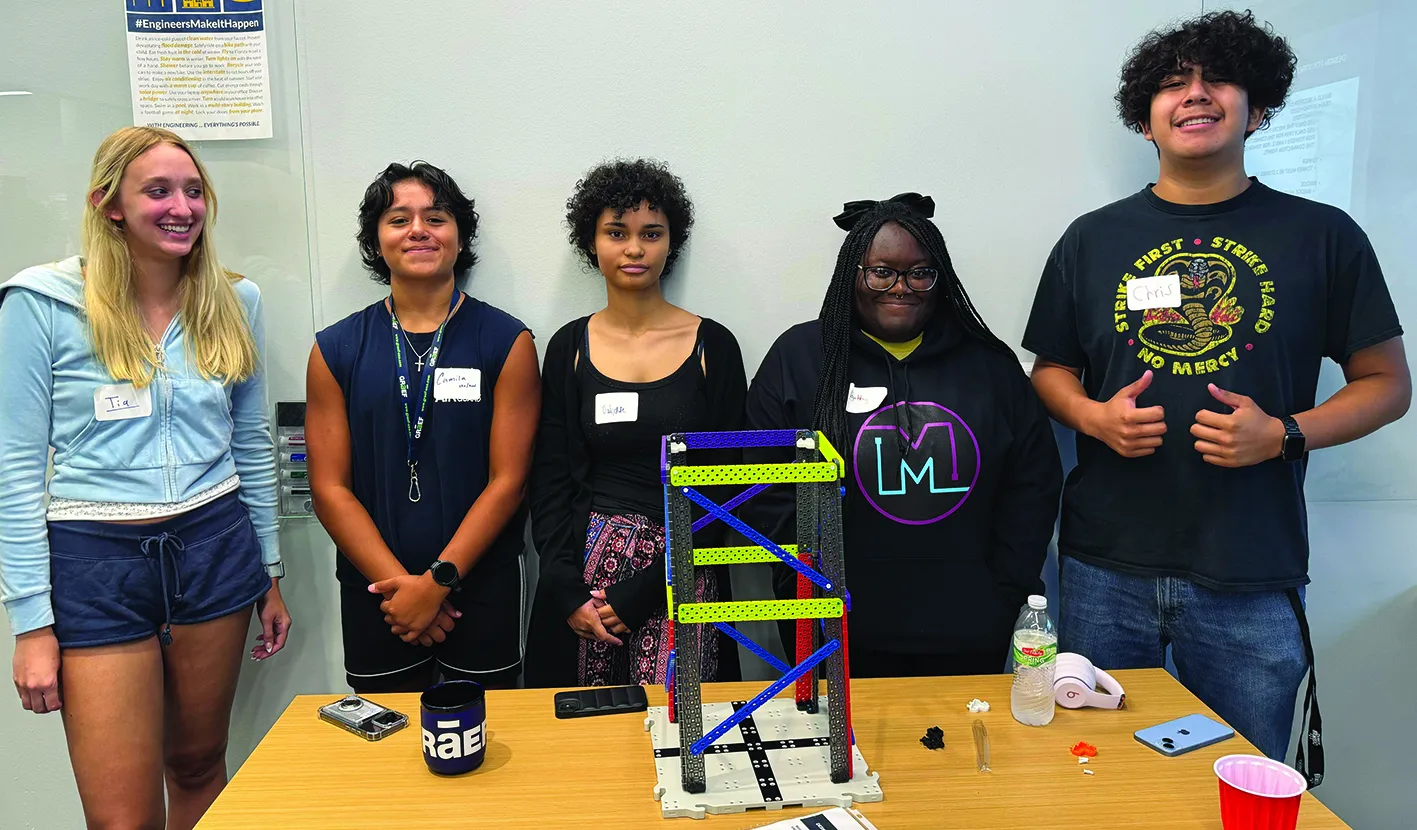 Madison College Early College STEM Academy students lined up for a photo, smiling, with projects on the table in front of them.