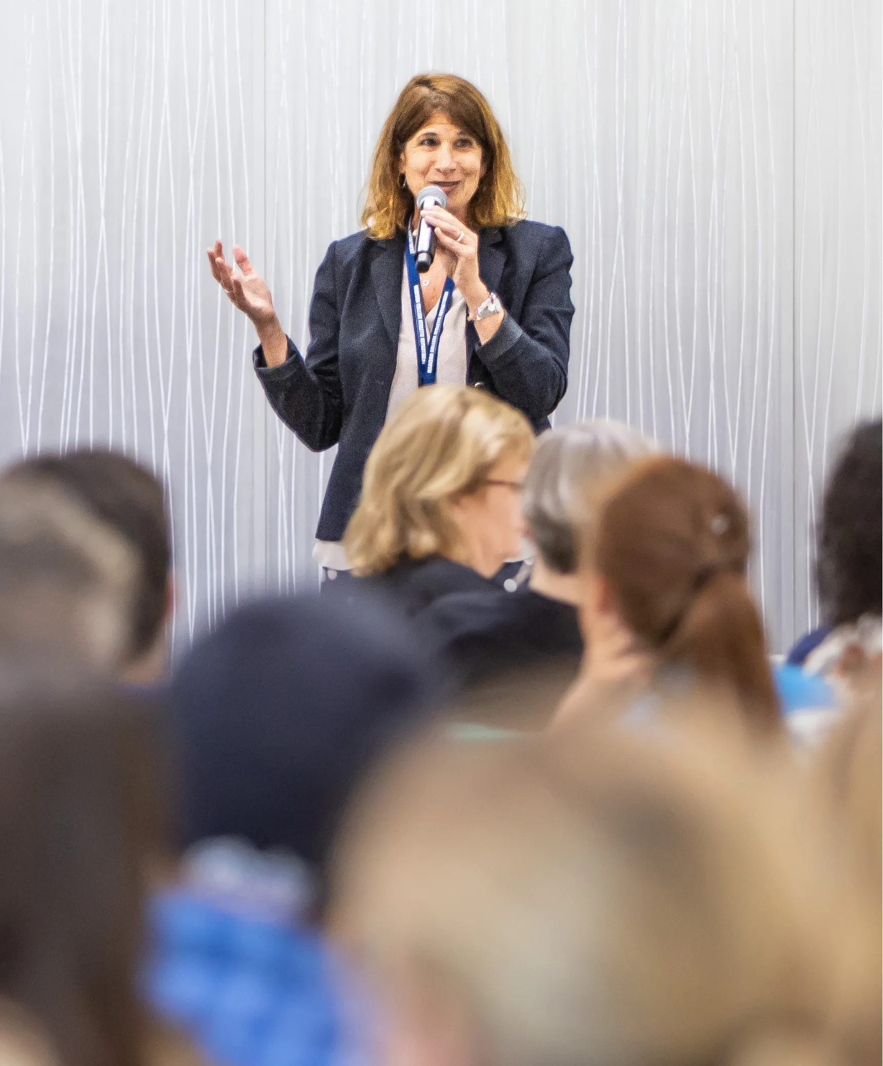 Dr. Berne holding a microphone speaking to a seated audience