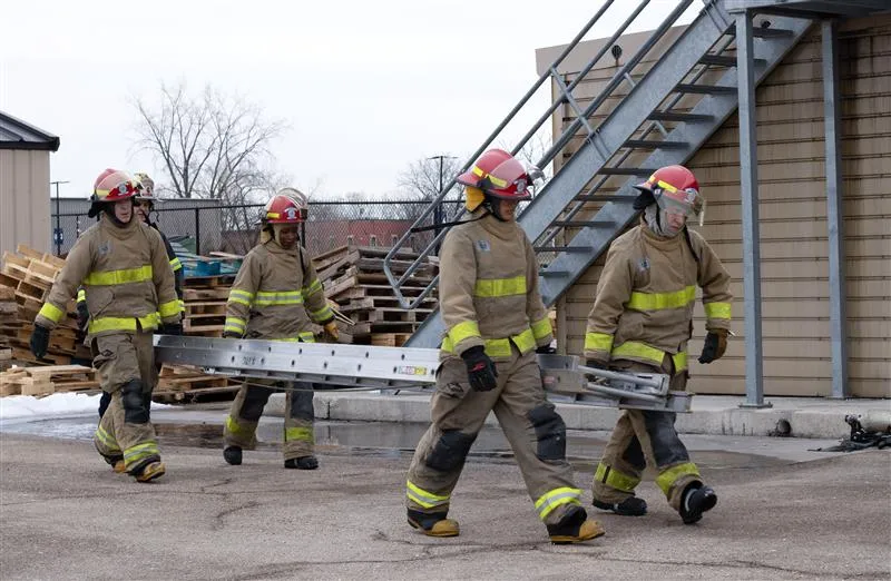 Four firemen carrying an extension ladder