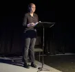 A young woman on an stage reading from a music stand