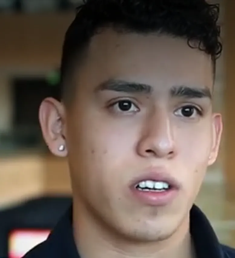 Male student with dark hair and dark eye, facing camera and talking.
