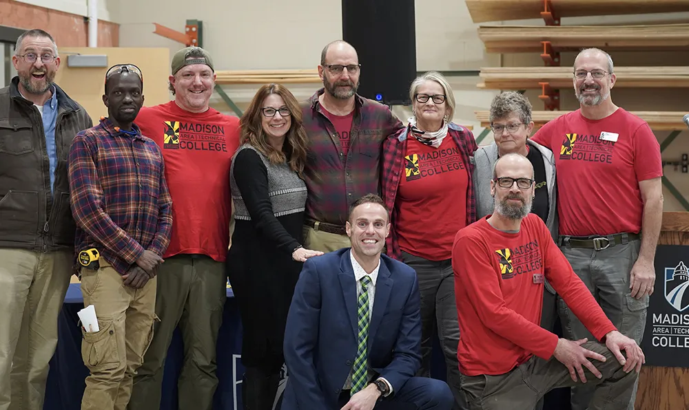 Faculty, staff and students pose of a photo inside the classroom of the new Construction and Remodeling space.