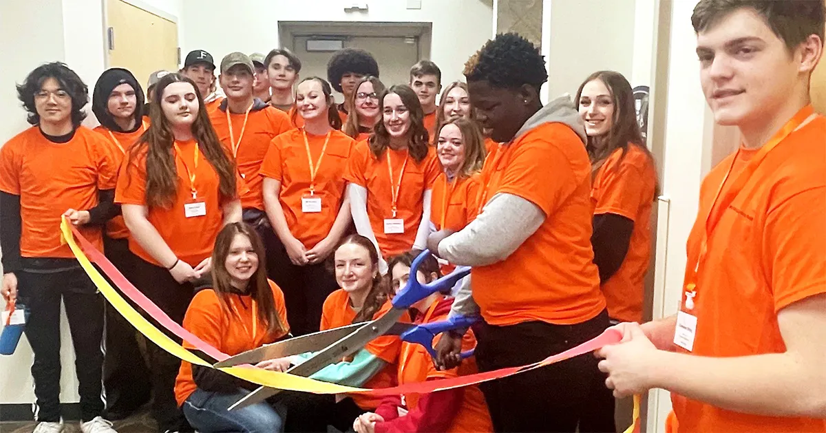 Students cutting ribbon with large scissors at Mini Manufacturing World