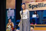 Contestant number 5 smiles at the microphone of the 25th Annual Putnam County Spelling Bee
