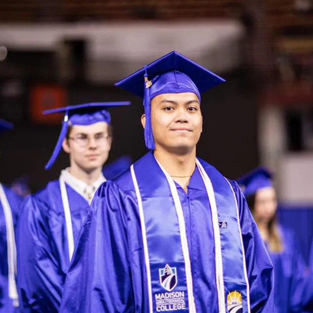 Two Madison College students in blue cap and gown with RISE sash