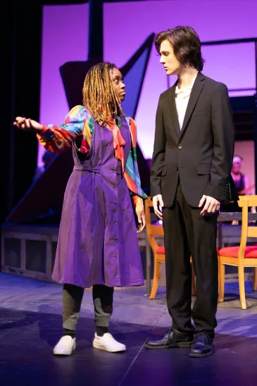 A man in a black suit with no tie and a woman in a purple dress in a scene from Rock of Ages