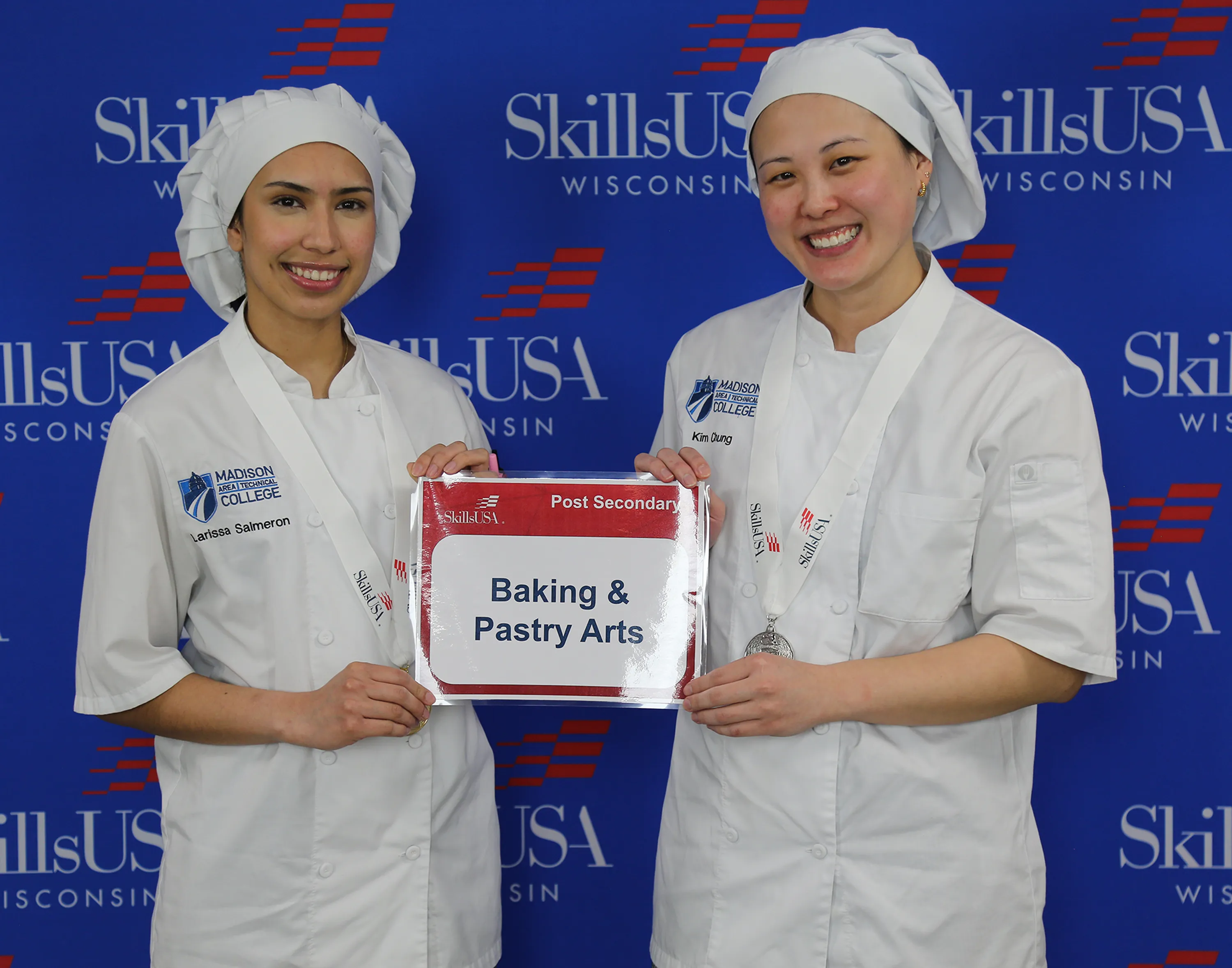 Two students with white baker hats and shirts, posing with certificate.