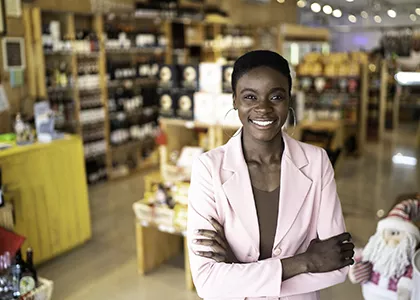 A smiling woman standing in front of her storefront.