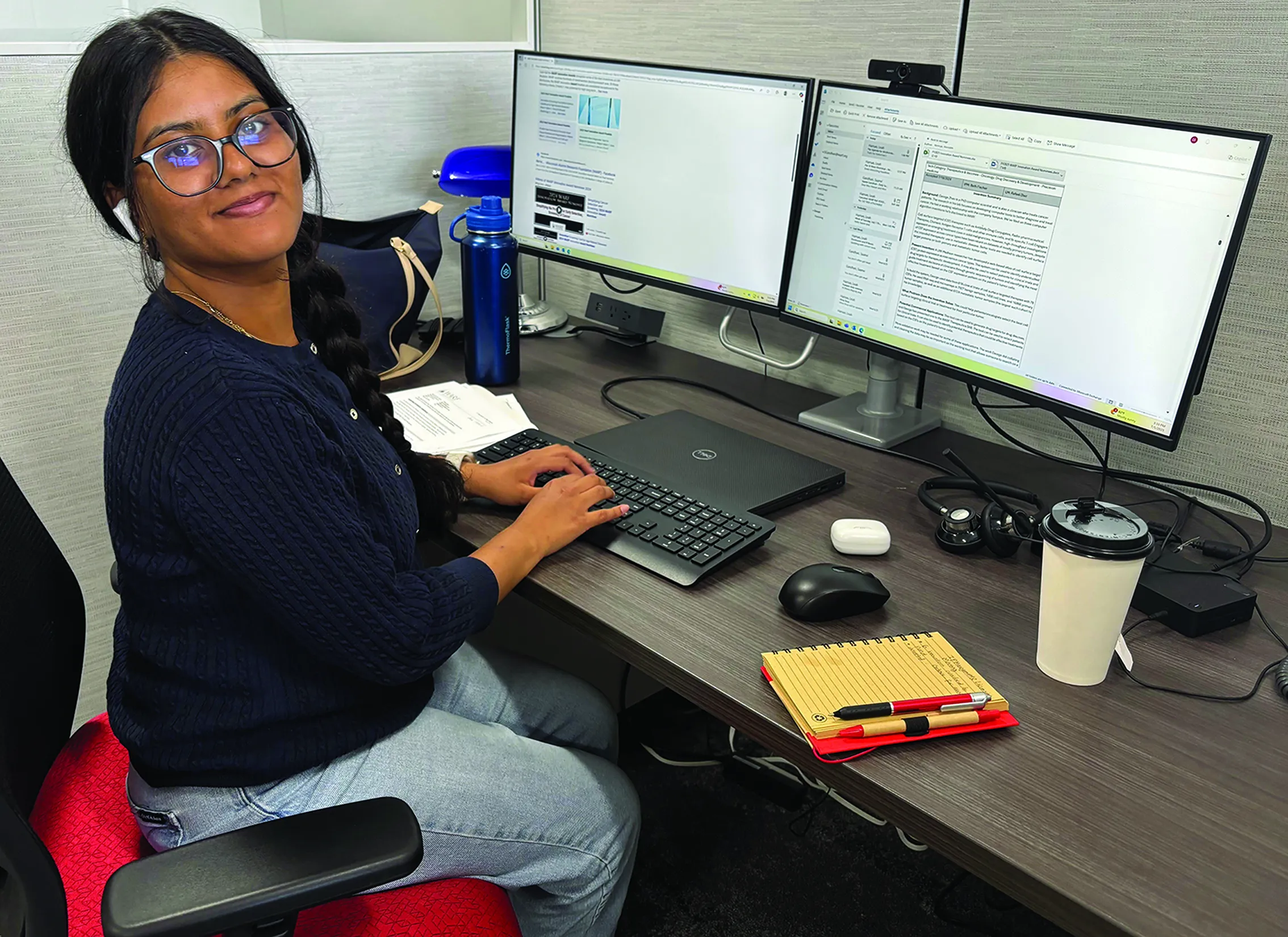 Student at a computer, turning around and smiling at camera.
