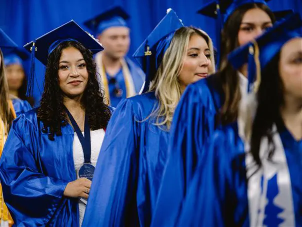 Students with blue cap and gowns at commencement.