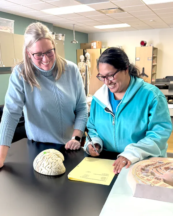 Student and teacher looking at a model of the human brain in an Anatomy and Physiology classroom